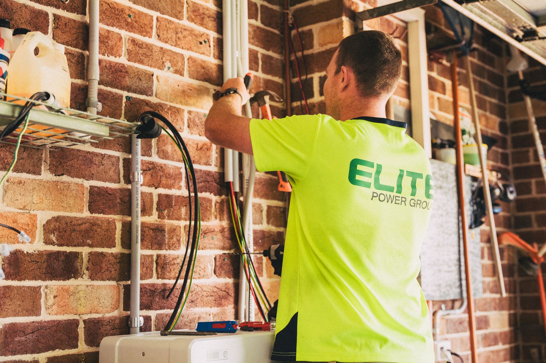 Installateur trekt kabels langs de wand richting de meterkast